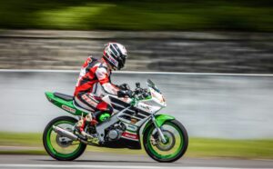 pilot de course sur moto verte sur circuit à pleine vitesse